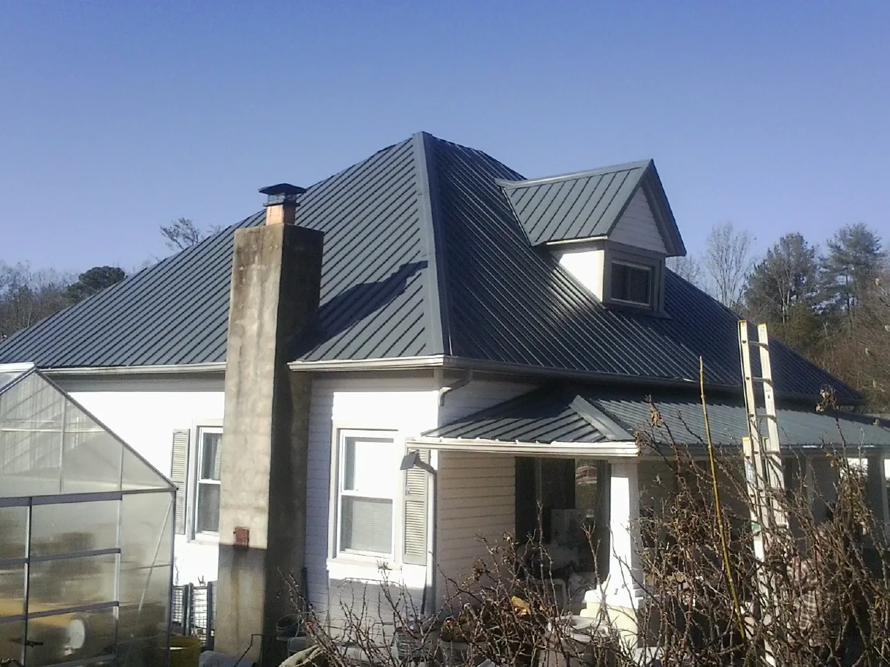 Dark blue standing seam metal roof on a white farmhouse with dormer — Slate & Tile Roof Repair by Roofing Brothers in High Falls