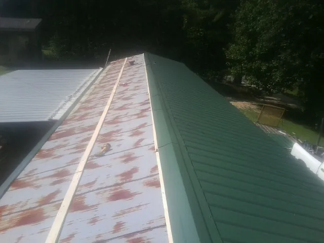 Old rusted panels beside newly installed green metal roofing — Wind Damage Roof Repair by Roofing Brothers in High Falls