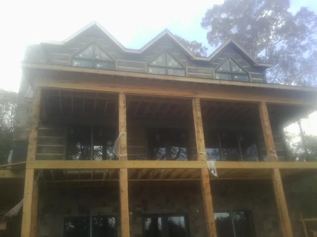 Dormers and porch framing on a large log home under construction — Roof Coating work by our crew in High Falls