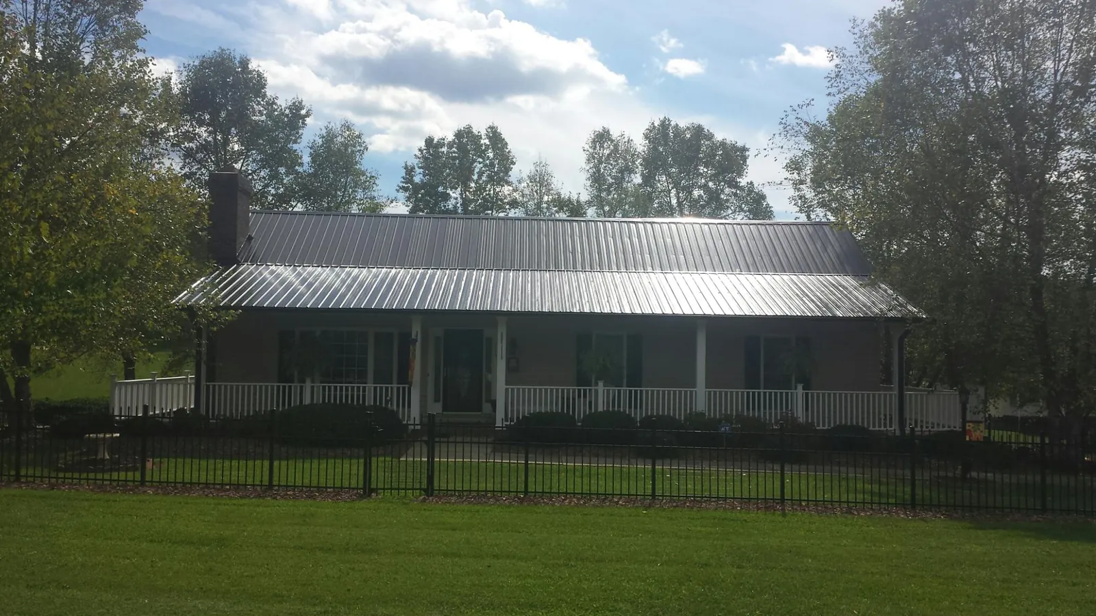 Gray metal roof on a brick ranch with a full width front porch — Gutter Guard Installation work by our crew in High Falls